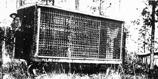 Horse drawn metal cage is rectangular in shape.