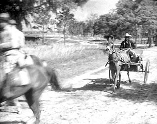 Two officers on horseback and man in wagon with bloodhound