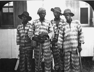 Four inmates standing together in striped uniforms