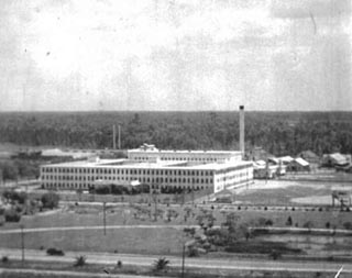 Aerial view of large, white retangular building with small windows.