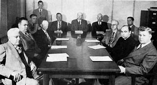 Approx. 12 men sitting around a large conference table.