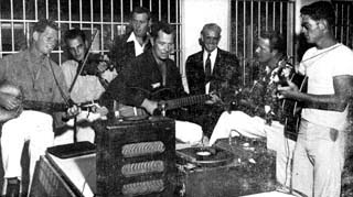 Seven men with guitars, banjo, and record player.