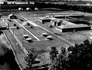 Aerial view of fenced prison.  Chapel, sidewalks and dorms are shown.