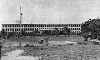 Three story, flat top building with many small windows.