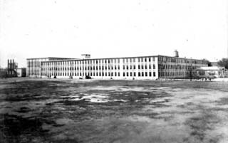 Aerial view of large, 3 story block buidling with uniform, small windows.