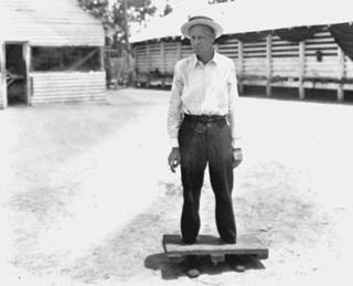 Photo of wooden stocks around a man's ankles.