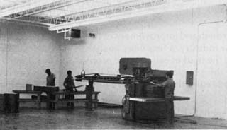 Large room with 2 inmates and a large machine.