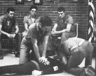 Inmate performing CPR on dummy while other inmates watch