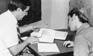 Correctional Officer and inmate looking at book.