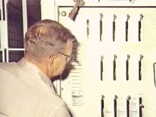 Officer with back to camera turning large silver dial set in stone wall