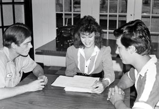 Young woman sitting at table with two young men.