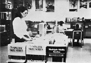 Large room with woman standing beside cart full of books.