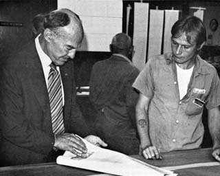 Man reviewing large sheet of paper while inmate watches