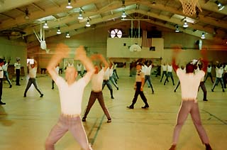 Inmates in gym doing jumping jacks