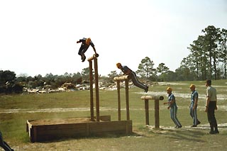 Inmates climbing three wooden arches and jumping off the last