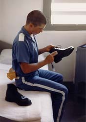 Inmate sitting on bunk polishing his shoe.