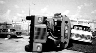 Large Bus laying on its side next to another damaged van.