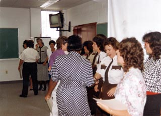 Approximately 15 women in meeting room standing and talking.