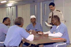 Inmates laughing, sitting around a table with correctional officer.