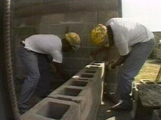 Inmates working with cement blocks.